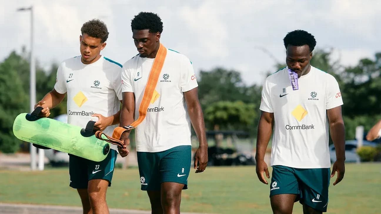Three players walking with training equipment outdoors