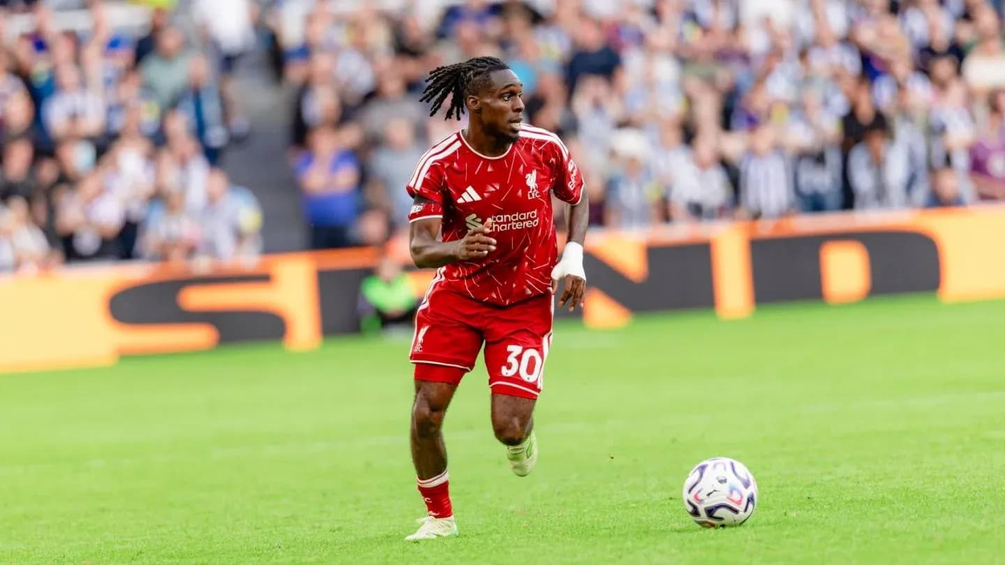 Player in red kit running with soccer ball on pitch