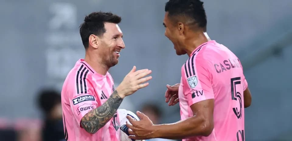 Players celebrating a goal in pink jerseys