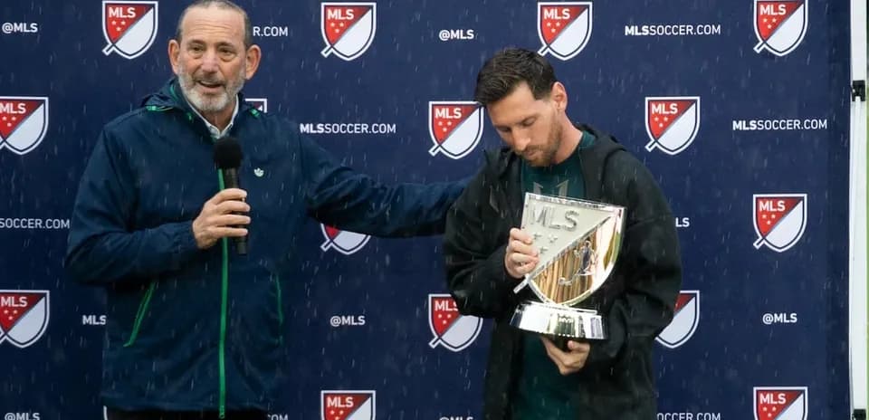 Player holding MLS trophy during rainy presentation