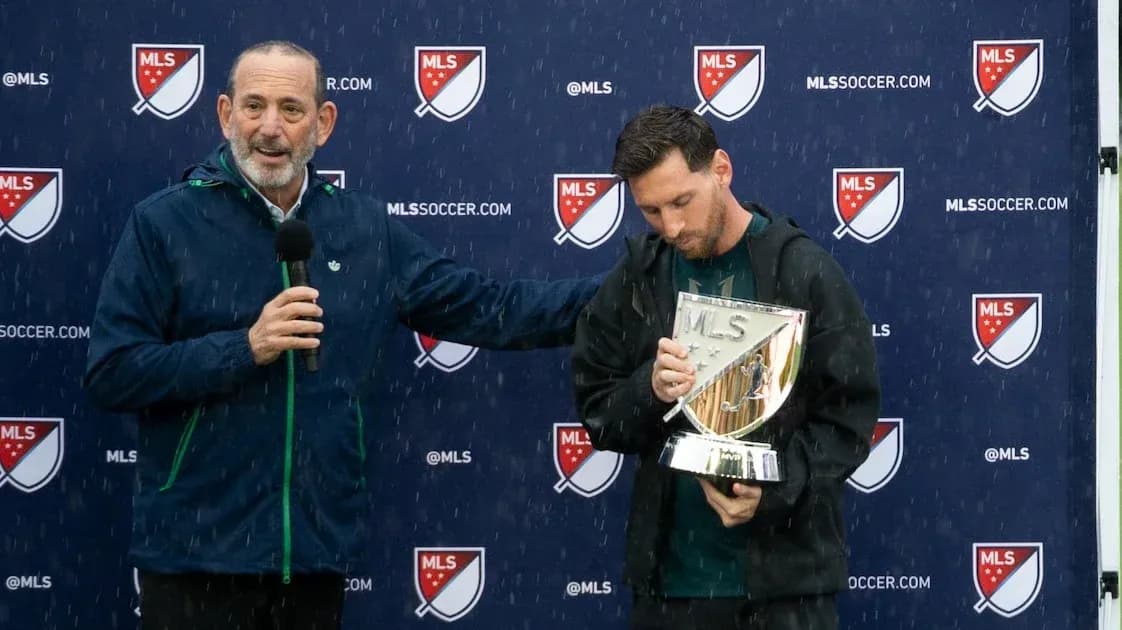 Player holding MLS trophy during rainy presentation