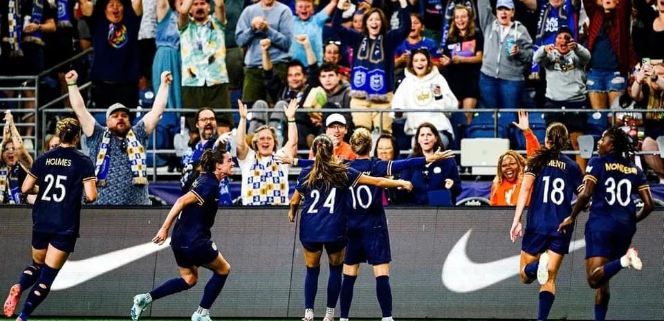 Players celebrating goal with excited fans