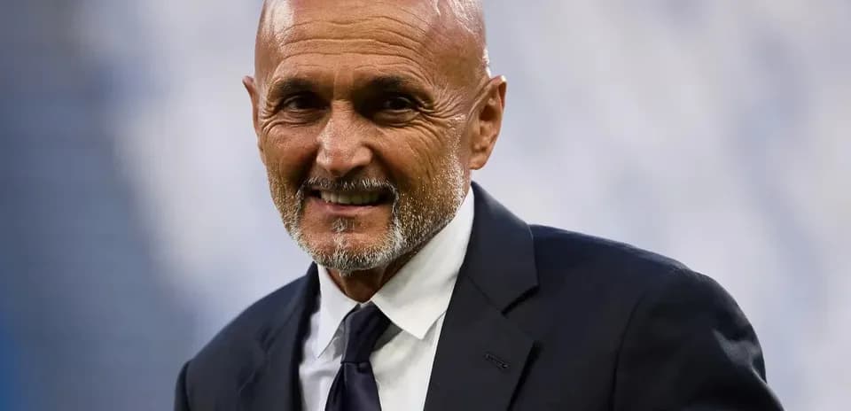 Coach smiling in a suit at stadium