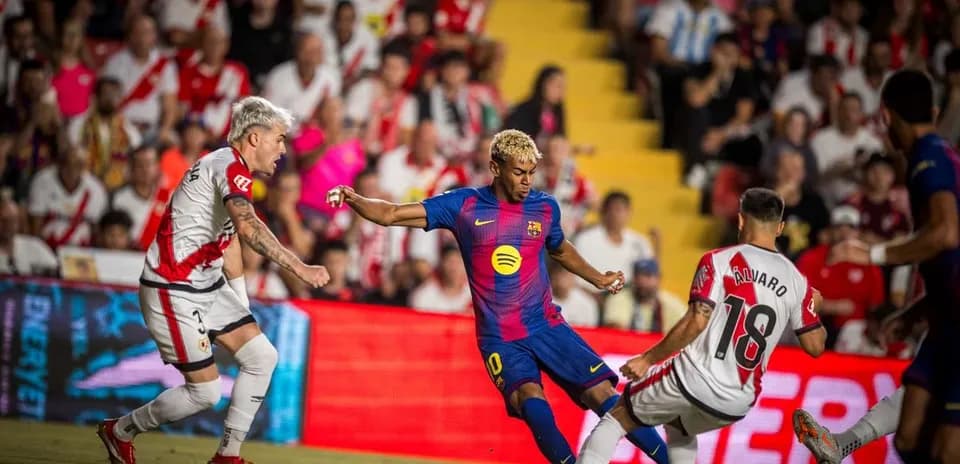 Barcelona player dribbling past Rayo Vallecano defenders