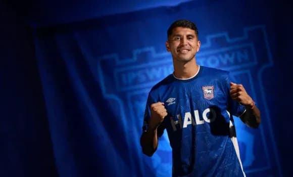 Player posing in Ipswich Town jersey with logo