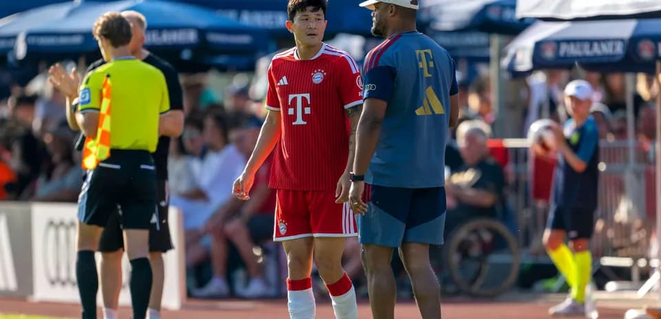 Bayern Munich player interacting with coach on sidelines