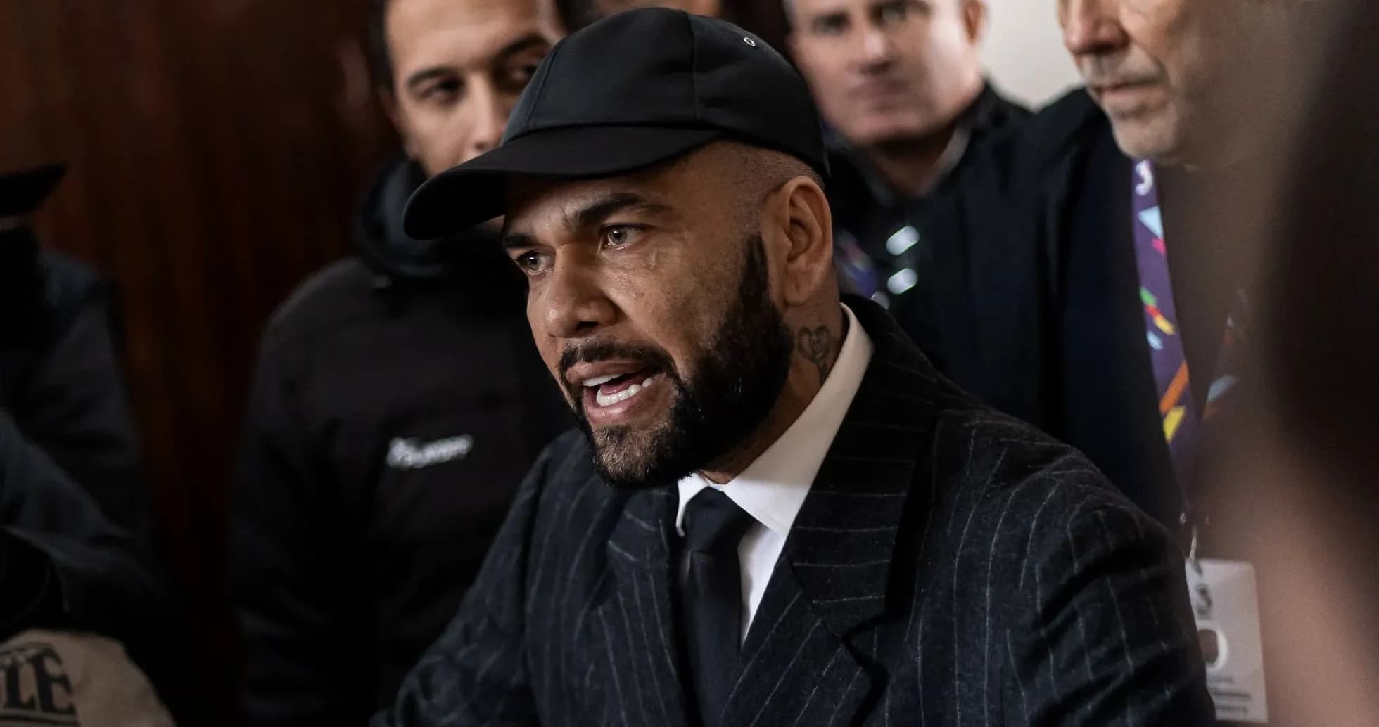 Person speaking surrounded by a crowd in formal attire