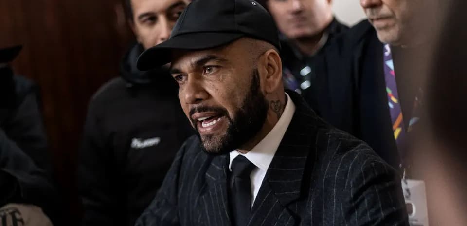 Person speaking surrounded by a crowd in formal attire