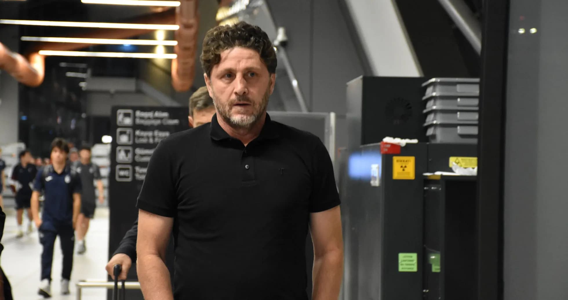Coach walking through an airport terminal with team
