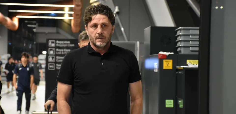 Coach walking through an airport terminal with team