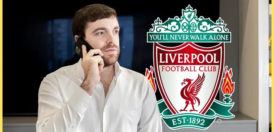 Person talking on phone near Liverpool FC logo