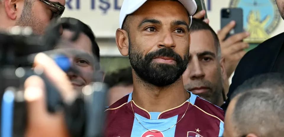 Football player in Trabzonspor jersey surrounded by fans