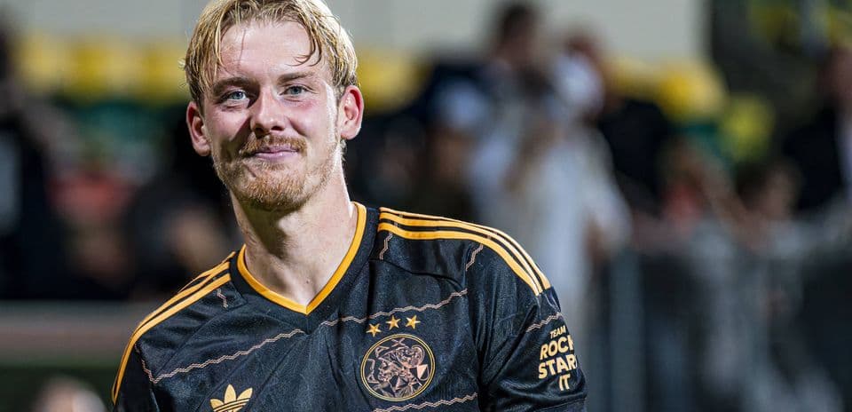 Player smiling in Ajax black jersey after match