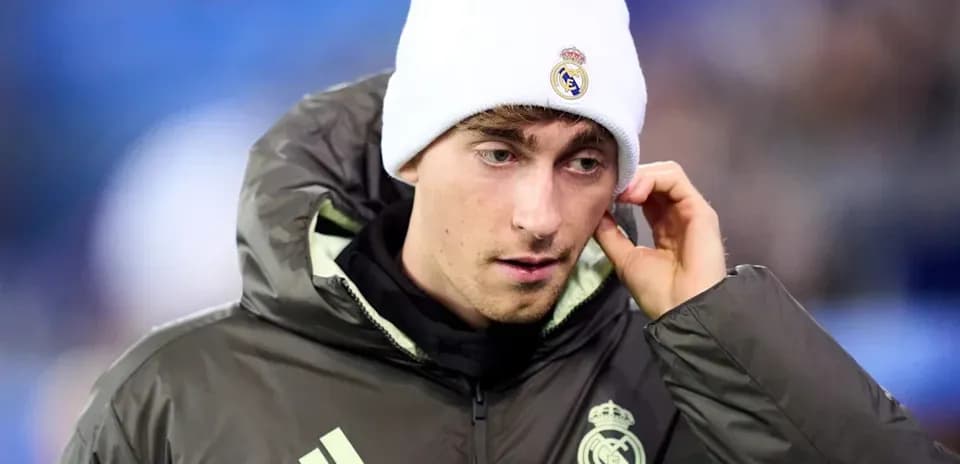 Player in Real Madrid jacket and beanie on pitch