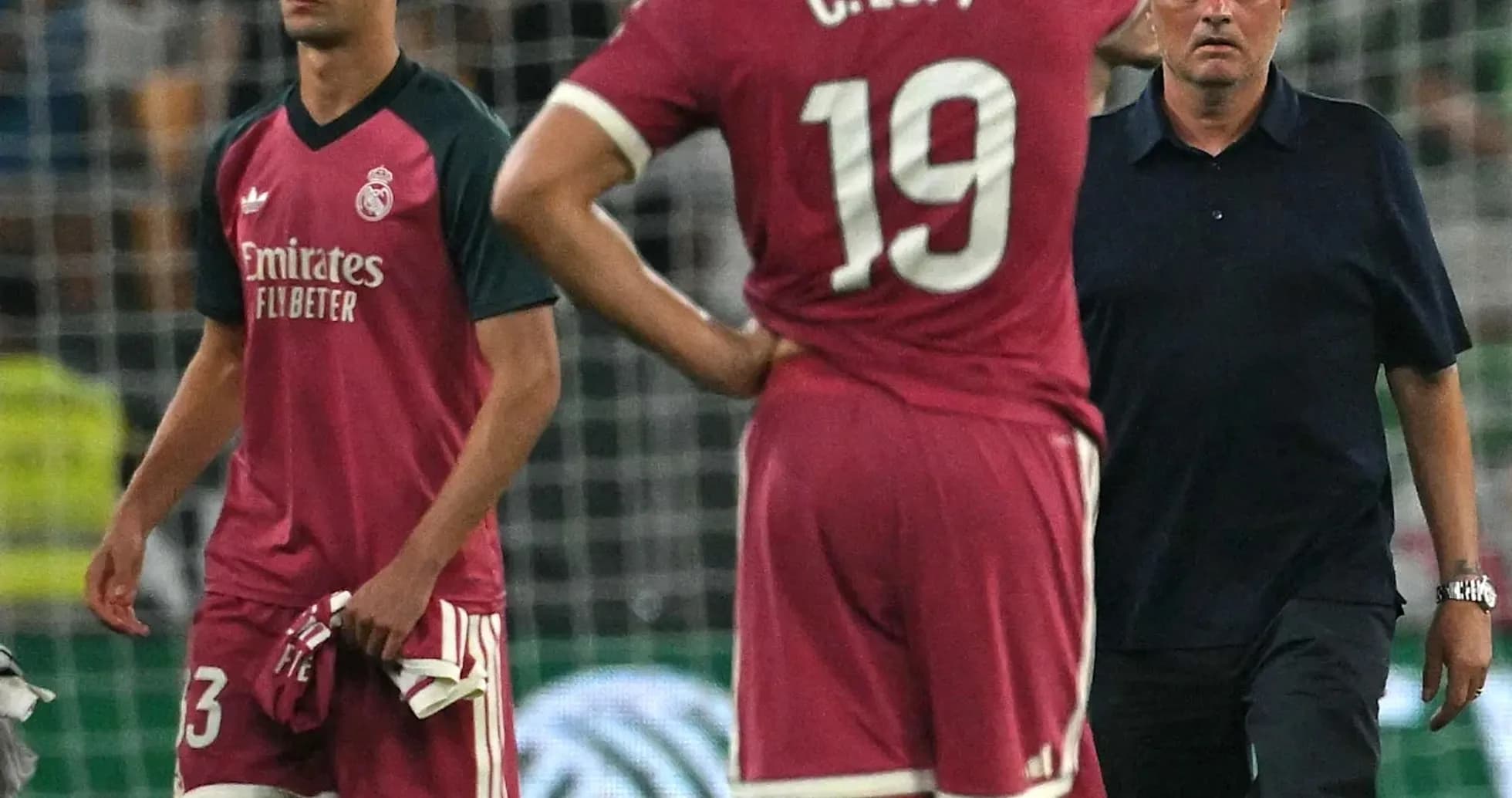 Players and coach during match, showing concern