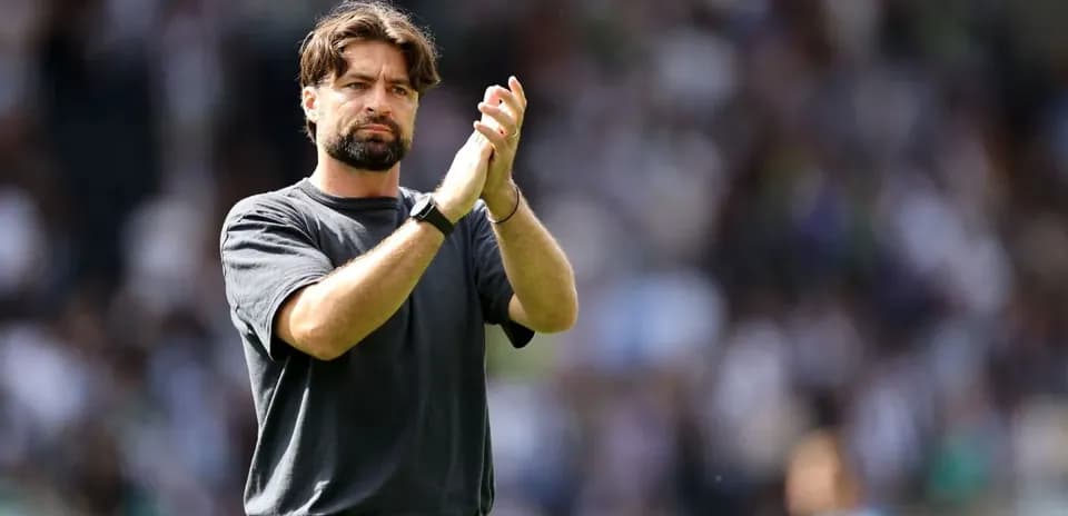 Coach applauding fans in stadium after match