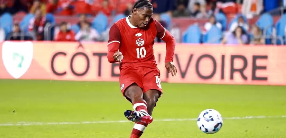 Player in red jersey kicking soccer ball on field