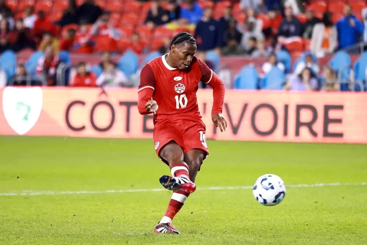 Player in red jersey kicking soccer ball on field