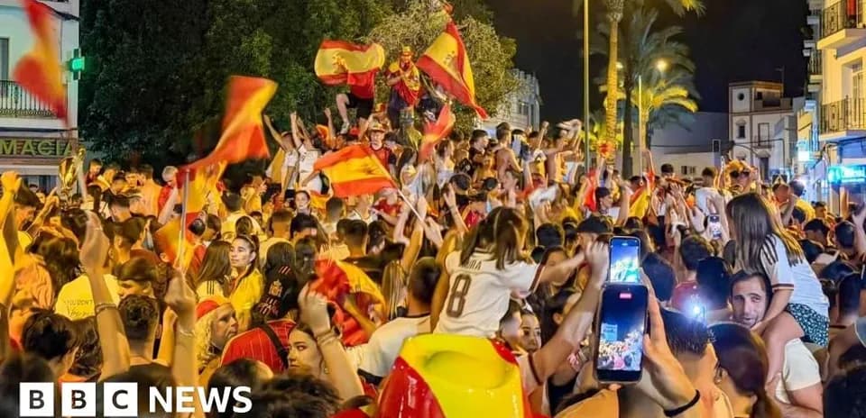 Crowd celebrating with flags in street at night