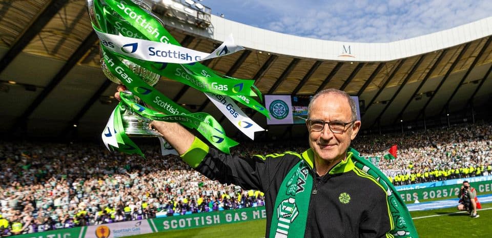 Man holding trophy with green ribbons at stadium