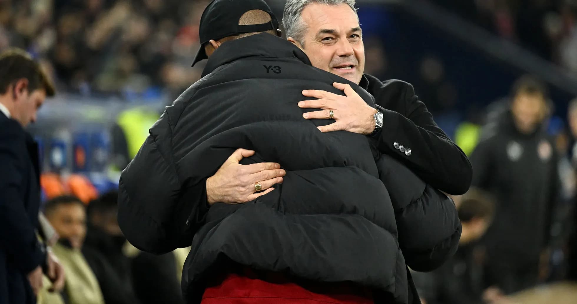 Two coaches embracing on the sidelines after match