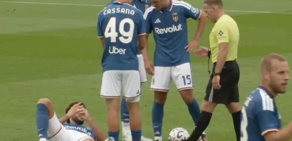 Player down on pitch with teammates and referee nearby