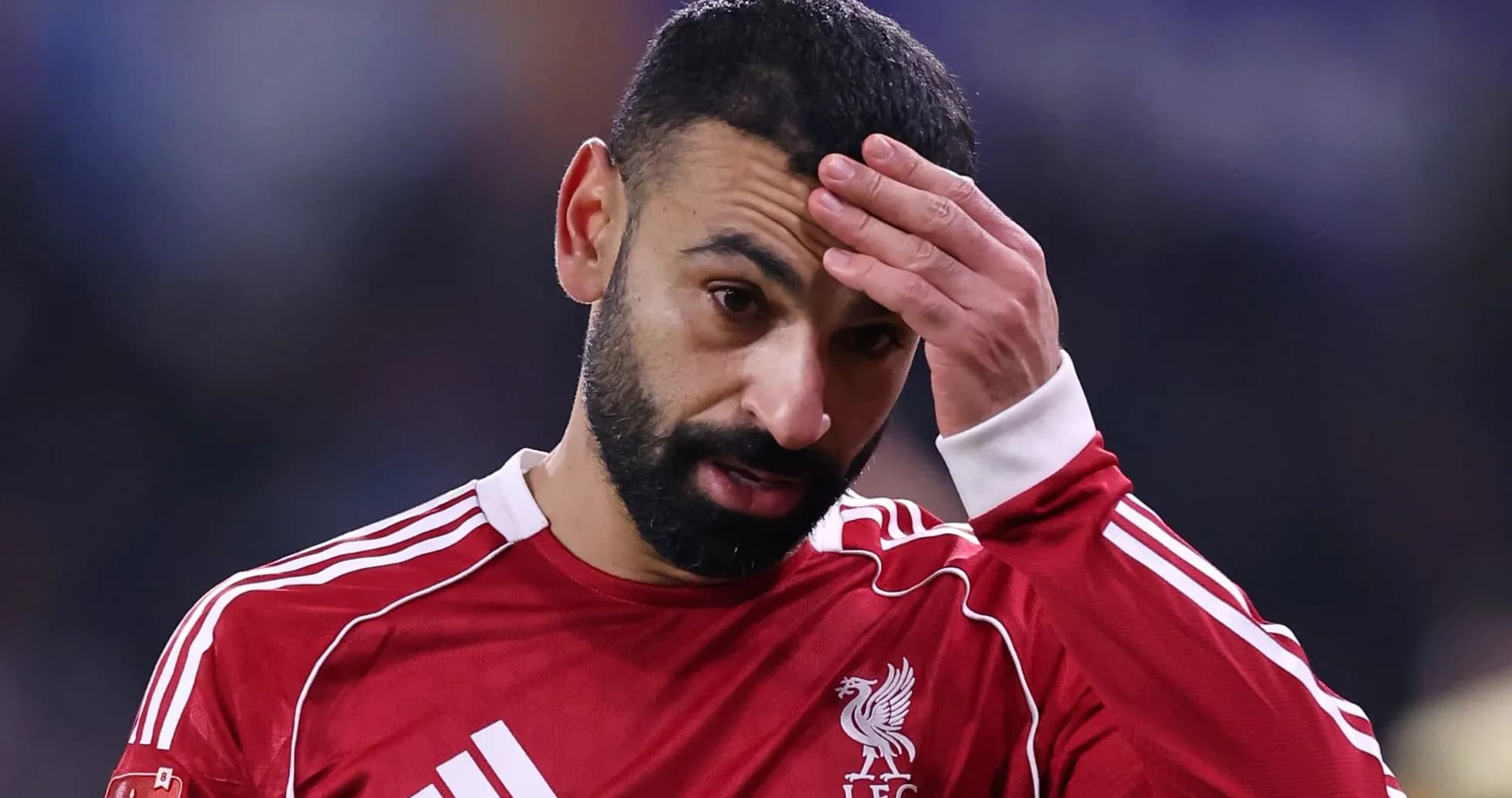 Player with hand on forehead wearing Liverpool jersey