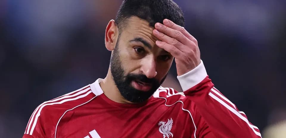 Player with hand on forehead wearing Liverpool jersey