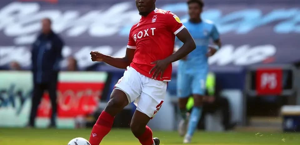 Player in red jersey dribbling the ball on pitch