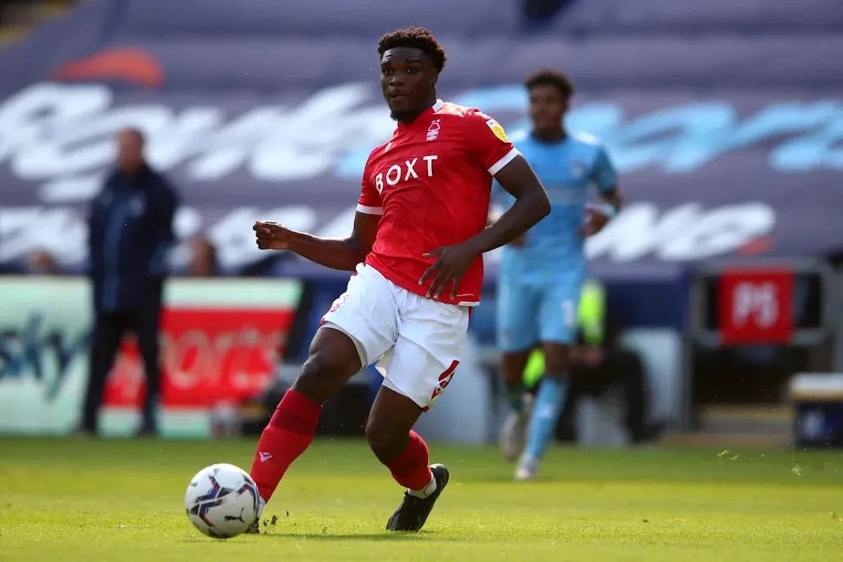 Player in red jersey dribbling the ball on pitch