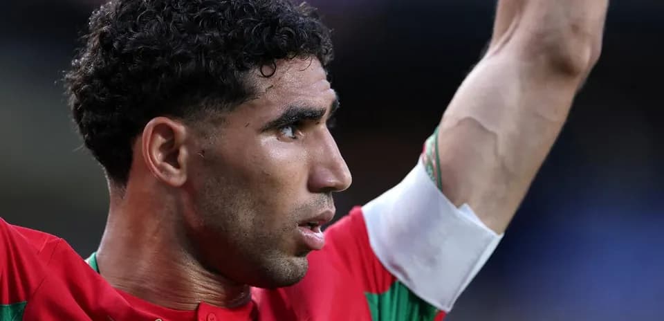 Player celebrating with raised arm wearing Morocco jersey