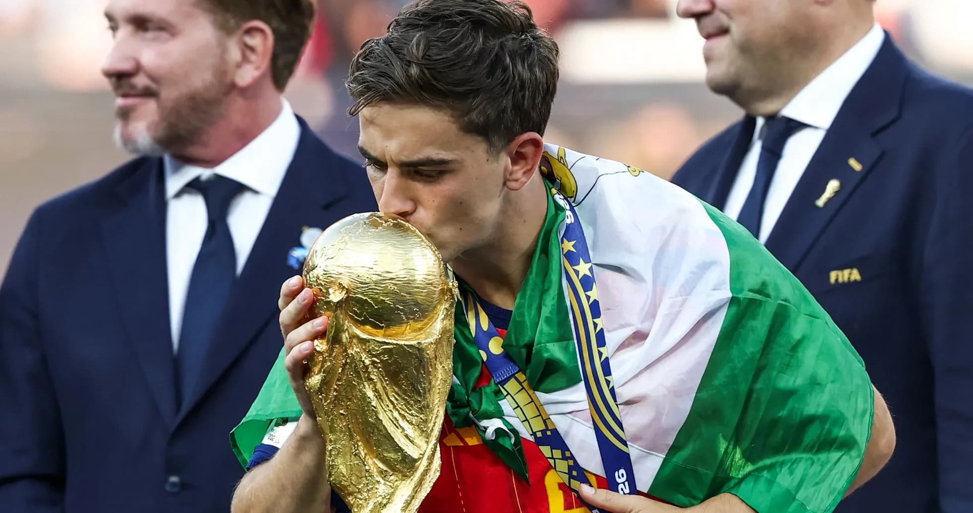 Player kissing World Cup trophy with flag draped