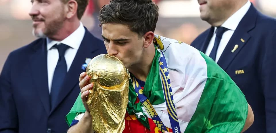 Player kissing World Cup trophy with flag draped