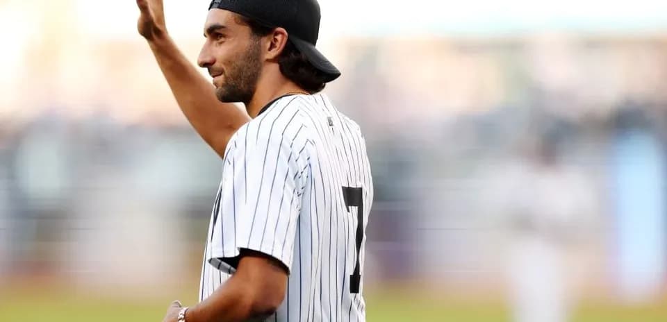 Man waving while wearing a baseball jersey