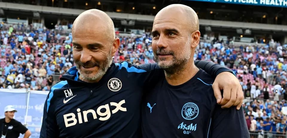 Two football coaches smiling together on the pitch