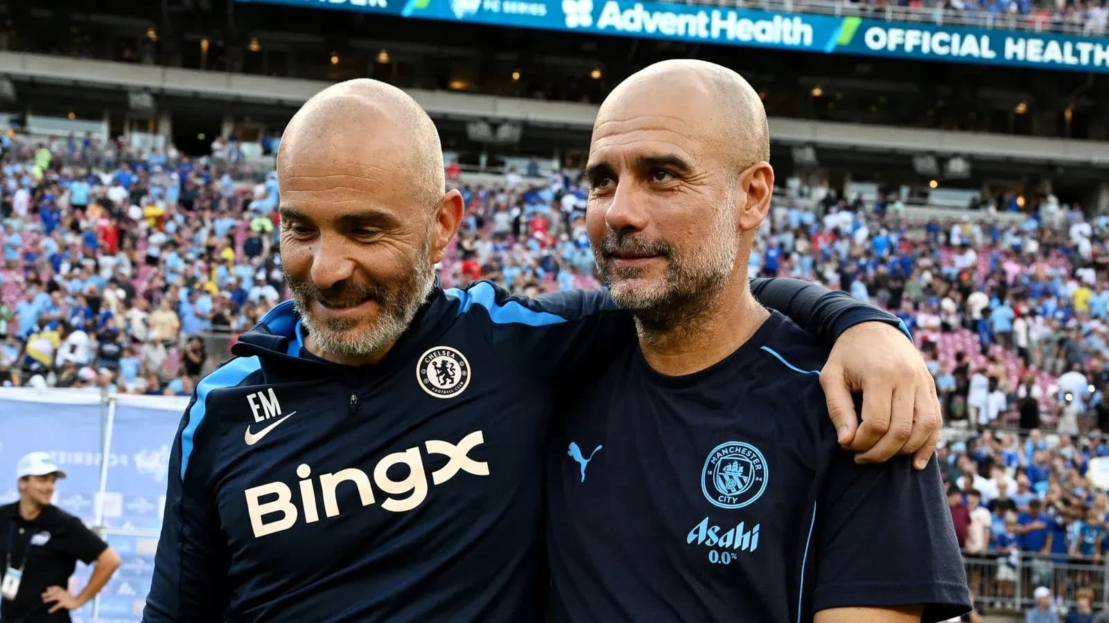 Two football coaches smiling together on the pitch