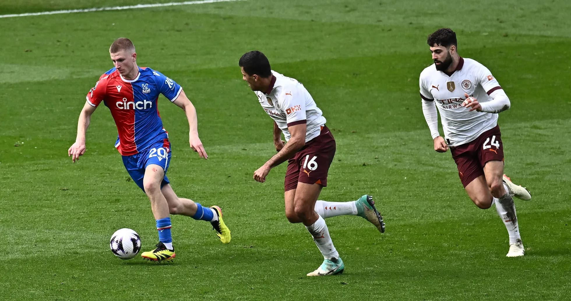 Player in blue shirt dribbling past two defenders