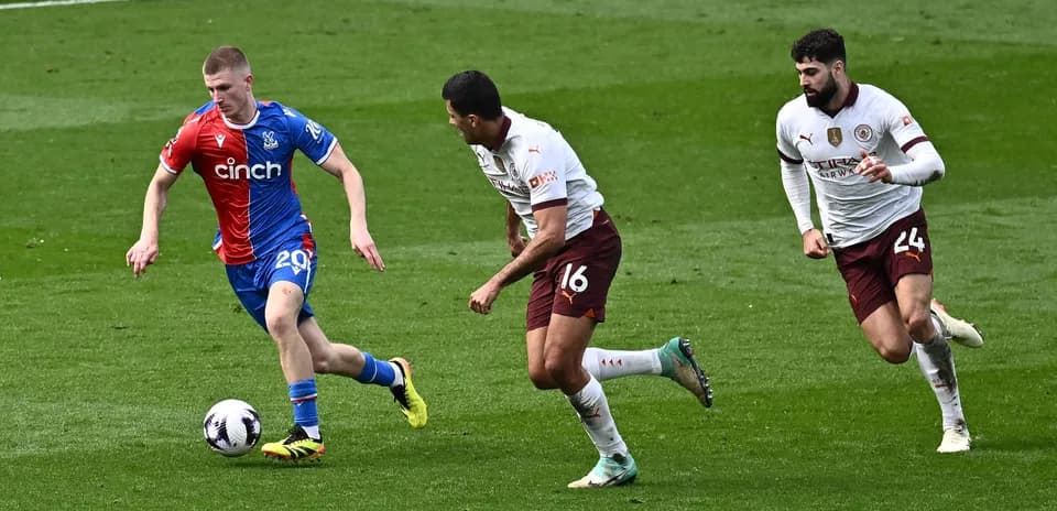 Player in blue shirt dribbling past two defenders