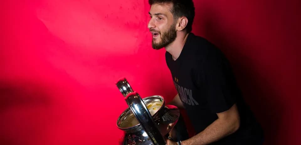 Player posing with trophy against pink background