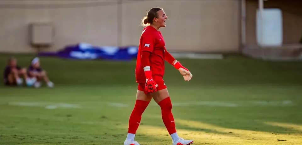 Goalkeeper in red kit celebrating on the field