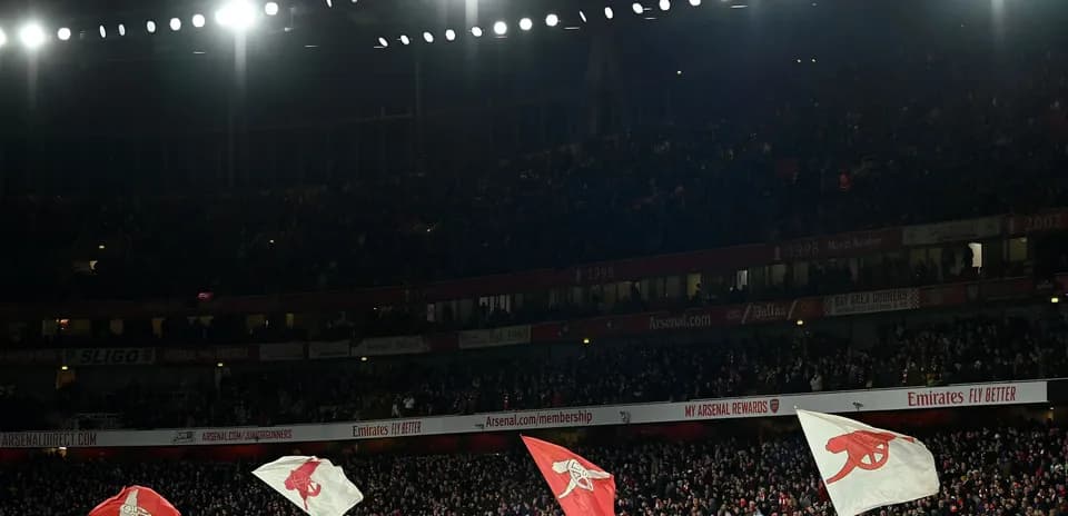 Arsenal fans waving flags in packed stadium