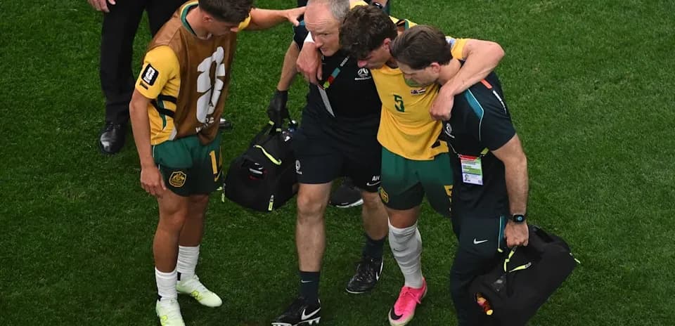 Player being assisted off the field by staff
