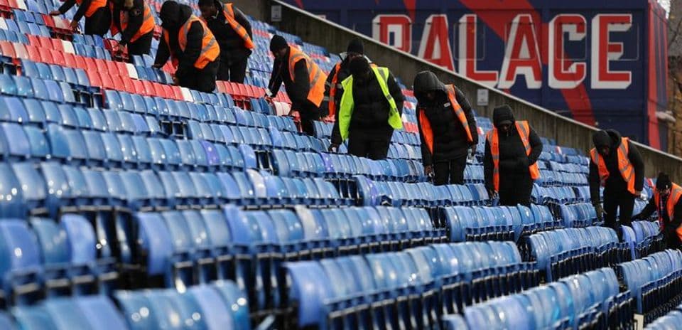 Staff cleaning empty stadium seats before event