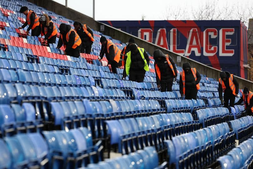 Staff cleaning empty stadium seats before event