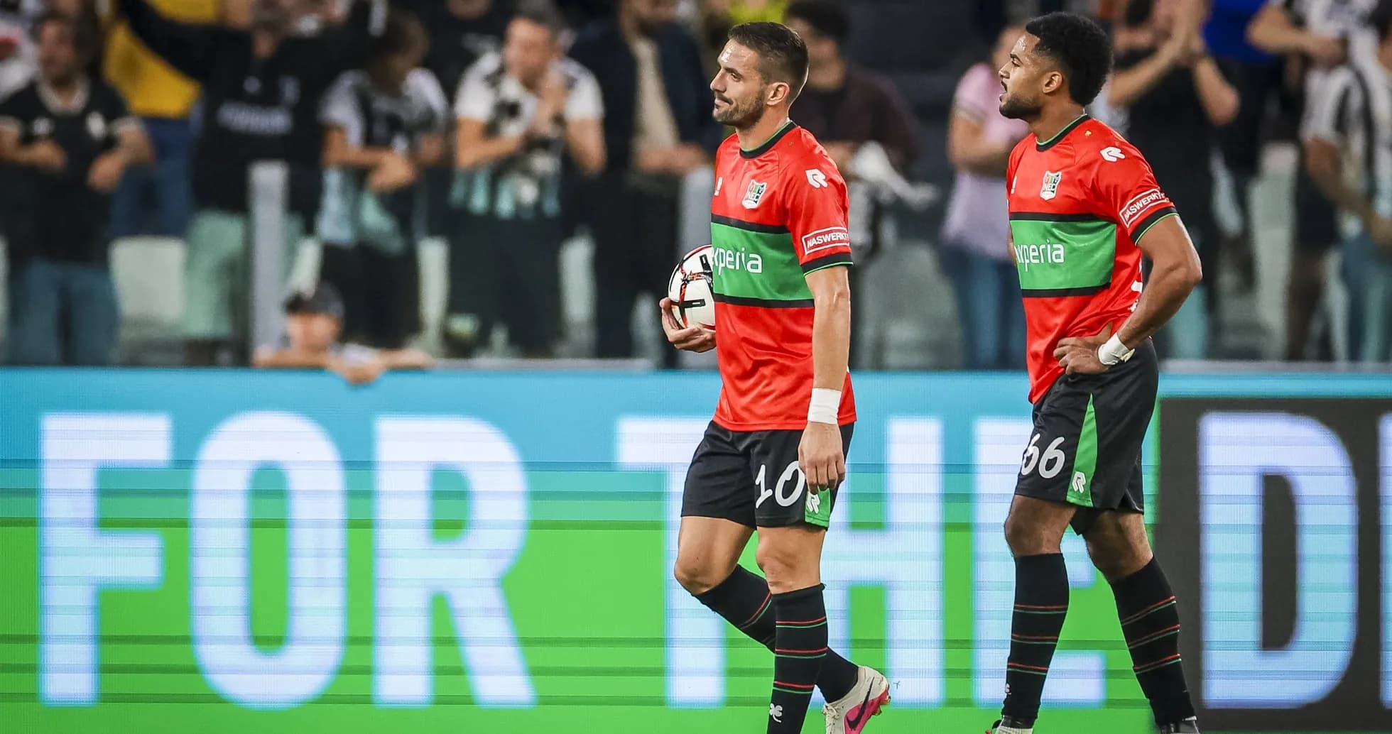 Two players walking off field holding a soccer ball