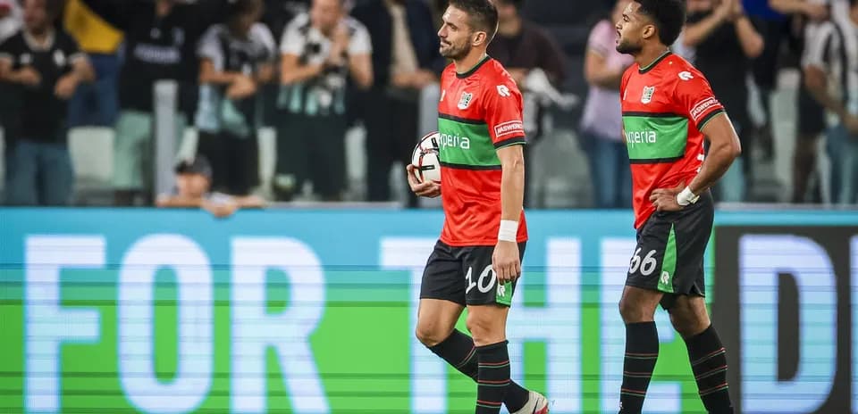 Two players walking off field holding a soccer ball