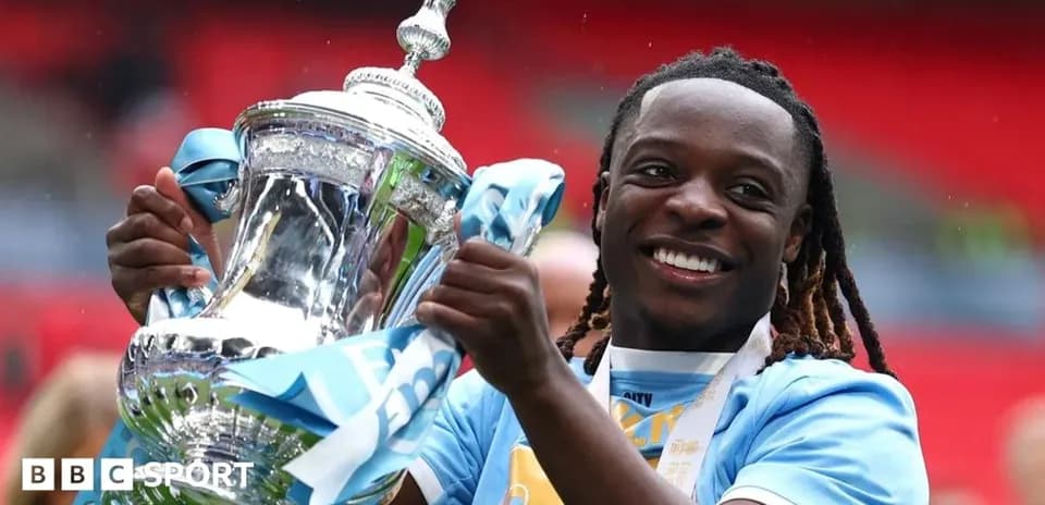 Player celebrating with trophy at Wembley Stadium
