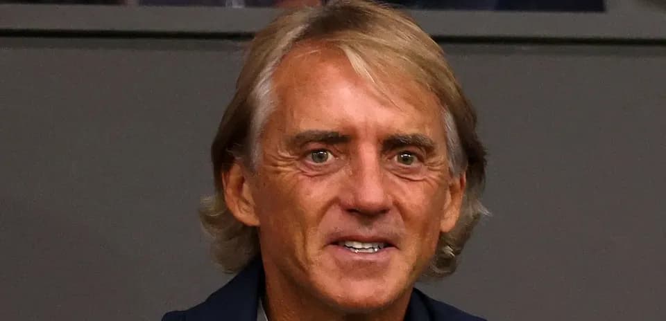 Man with light brown hair smiling in a venue