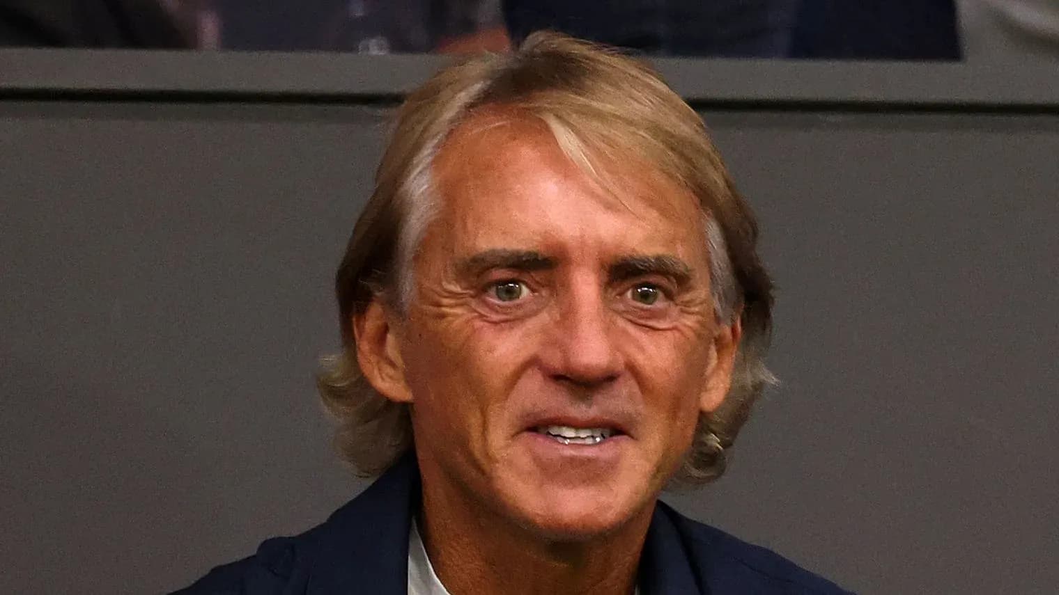 Man with light brown hair smiling in a venue