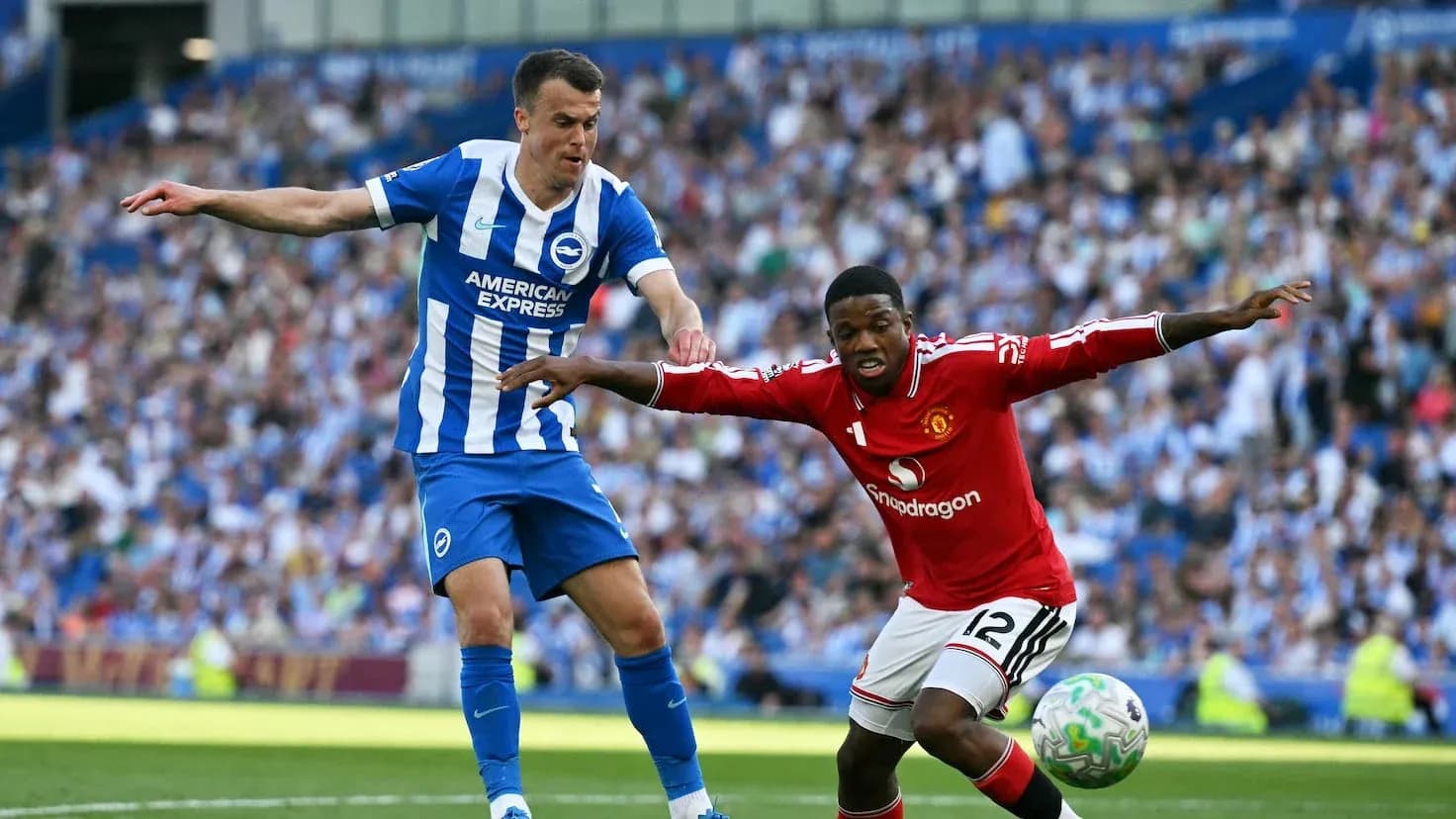 Brighton player challenging Manchester United opponent